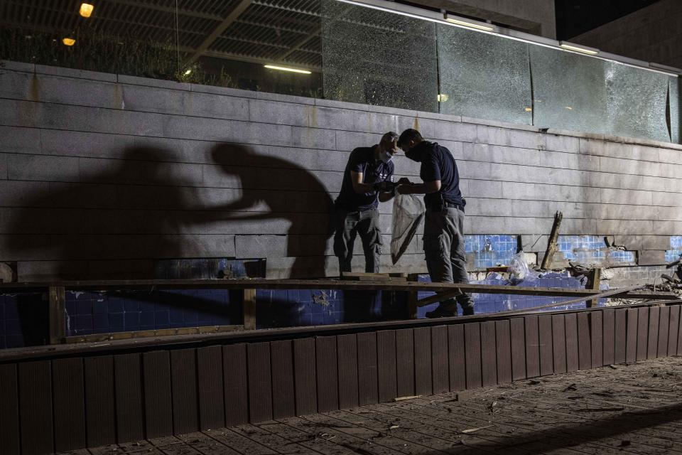 Israeli police inspect the damage at the site hit by a rocket fired by Palestinian militants from the Gaza Strip in the southern city of Ashdod, Israel, Tuesday, Sept. 15, 2020. The Israeli military says two rockets were fired from Gaza and one was intercepted by air defenses. Magen David Adom, the Israeli emergency service, says it treated two people for minor injuries from broken glass. (AP Photo/Tsafrir Abayov)