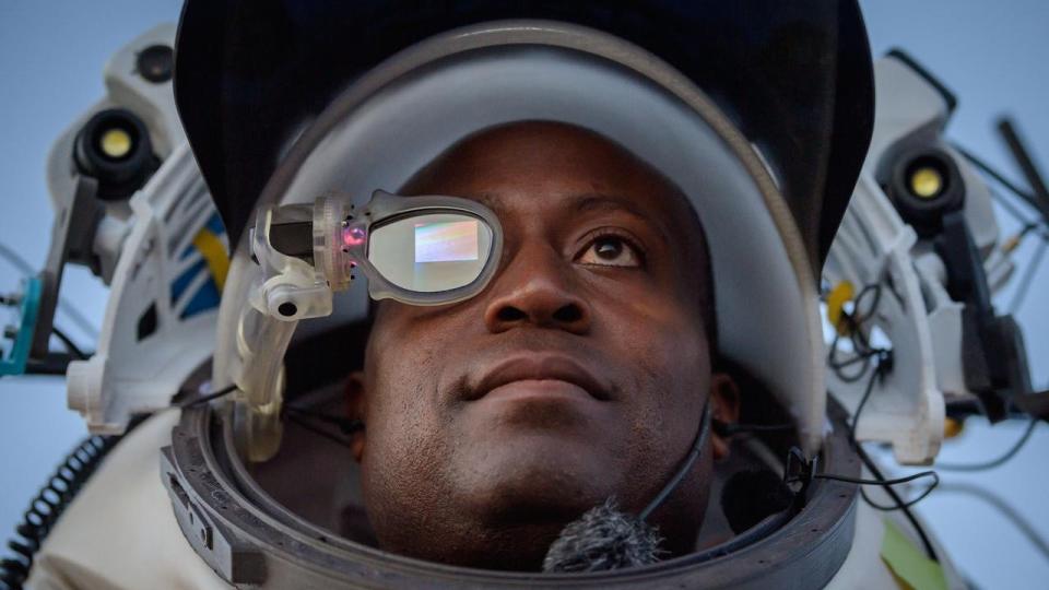 an astronaut in a simulated spacesuit. one of his eyes is covered in a glass for an augmented reality device