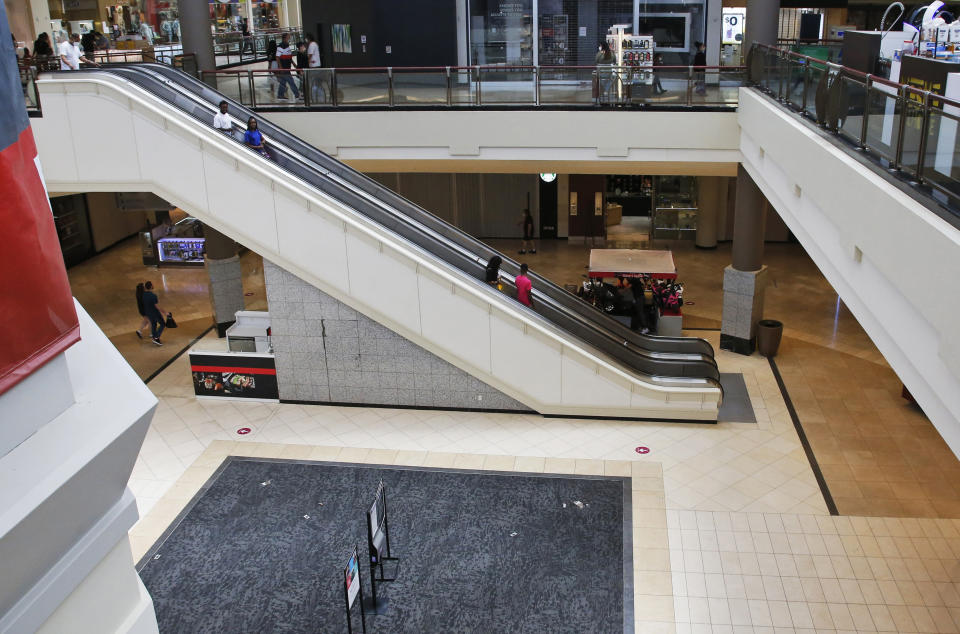 FILE - In this May 1, 2020, file photo, people ride down an escalator at a shopping mall in Oklahoma City as it reopens from its closure since mid-March due to coronavirus concerns. Many businesses are requiring customers and workers to sign forms saying they won't sue if they catch COVID-19. Businesses are afraid they could face lawsuits even if they follow social distancing and other government guidelines as they reopen across the U.S. after coronavirus shutdowns. (AP Photo/Sue Ogrocki, File)