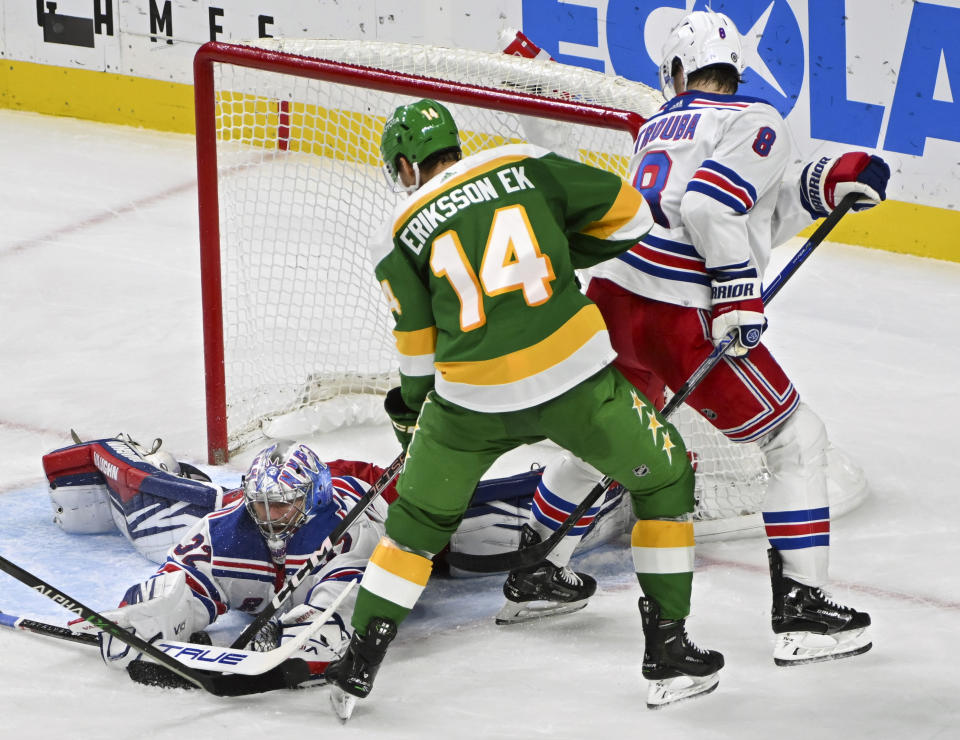 New York Rangers goalie Jonathan Quick, left, makes a save on a shot by Minnesota Wild center Joel Eriksson Ek (14) as Rangers defenseman Jacob Trouba (8) tries to clear the net during the third period of an NHL hockey game Saturday, Nov. 4, 2023, in St. Paul, Minn. (AP Photo/Craig Lassig)