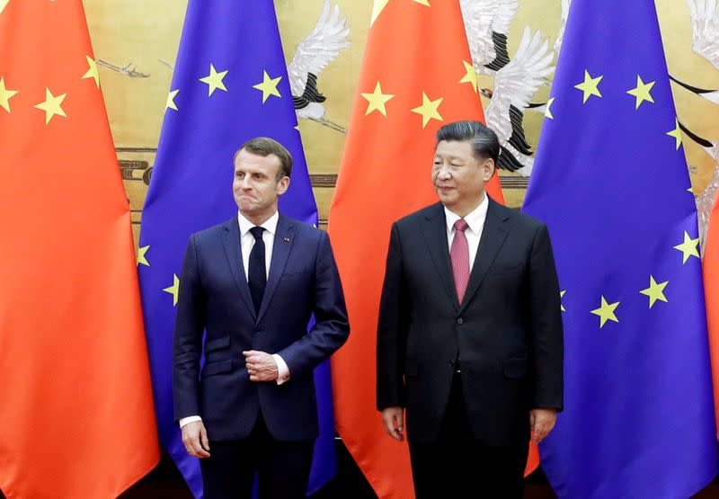 FILE PHOTO: Chinese President Xi Jinping and French President Emmanuel Macron stand in front of Chinese and EU flags at a signing ceremony inside the Great Hall of the People in Beijing