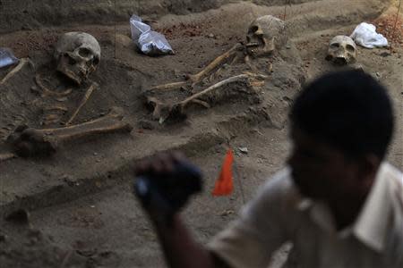A police officer takes a video of human skeletons at a construction site in the former war zone in Mannar, about 327 km (203 miles) from the capital Colombo, January 16, 2014. REUTERS/Dinuka Liyanawatte
