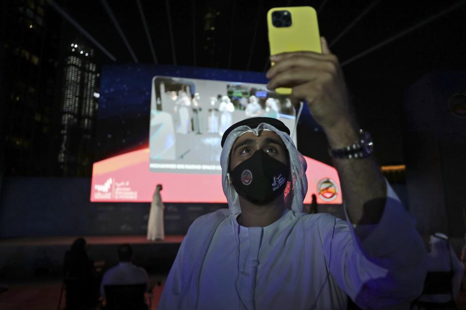 An Emirati man takes a video with his phone of the celebration after the Hope Probe enters Mars orbit as a part of the Emirates Mars mission, in Dubai, United Arab Emirates, Tuesday, Feb. 9, 2021. The spacecraft from the UAE swung into orbit around Mars in a triumph for the Arab world’s first interplanetary mission. It is the first of three robotic explorers arriving at the red planet over the next week and a half. (AP Photo/Kamran Jebreili)