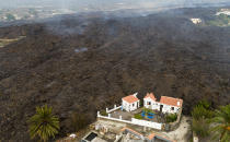 Lava from a volcano eruption flows destroying houses on the island of La Palma in the Canaries, Spain, Tuesday, Sept. 21, 2021. A dormant volcano on a small Spanish island in the Atlantic Ocean erupted on Sunday, forcing the evacuation of thousands of people. Huge plumes of black-and-white smoke shot out from a volcanic ridge where scientists had been monitoring the accumulation of molten lava below the surface. (AP Photo/Emilio Morenatti)