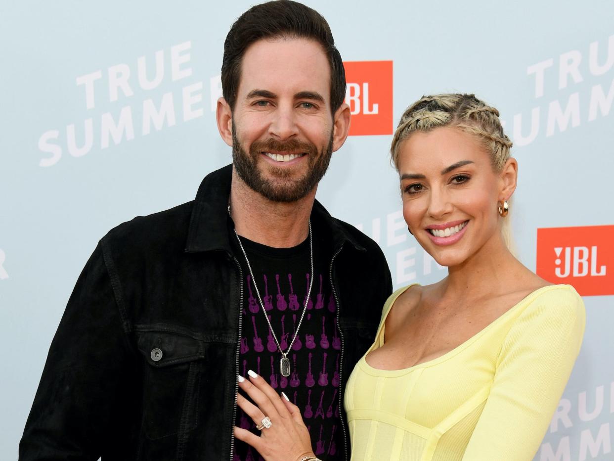 Tarek and Heather Rae El Moussa pose on a red carpet.