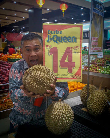 A man poses with a J-Queen durian in Jakarta, Indonesia January 25, 2019 in this picture obtained from social media. INSTAGRAM / @PLAZAASIA.OFFICIAL/via REUTERS