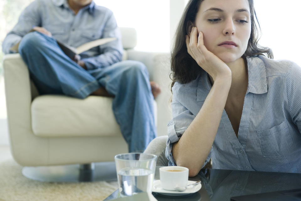 woman looking bored while her husband reads in the background