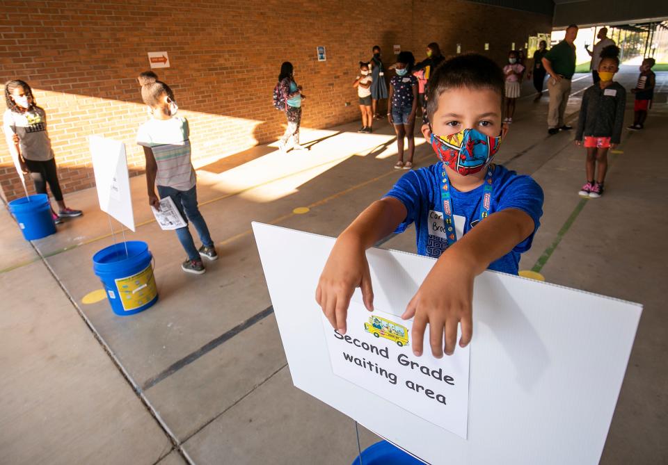 Brody Johnson, 7, an Evergreen Elementary School second-grader, stands on a dot in the second grade waiting area while practicing social distancing with his fellow classmates in July 2020.