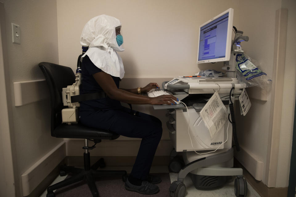A nurse wearing an air-purifying respirator works on a computer in a COVD-19 unit at El Centro Regional Medical Center in El Centro, Calif., Tuesday, July 21, 2020. (AP Photo/Jae C. Hong)