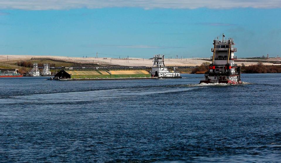 A loaded grain barge headed down the Snake River passes a tugboat headed upriver in Burbank near the confluence with the Columbia River.