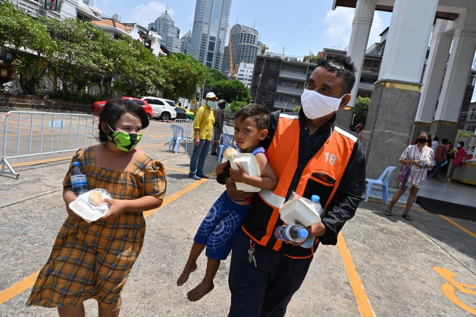 A motorcycle taxi driver, wearing a face mask as a preventive measure against the spread of the COVID-19 novel coronavirus, carries a boy after receiving food donations organised by the Holy Redeemer Catholic Church in Bangkok on May 6, 2020. (Photo by Romeo GACAD / AFP) (Photo by ROMEO GACAD/AFP via Getty Images)