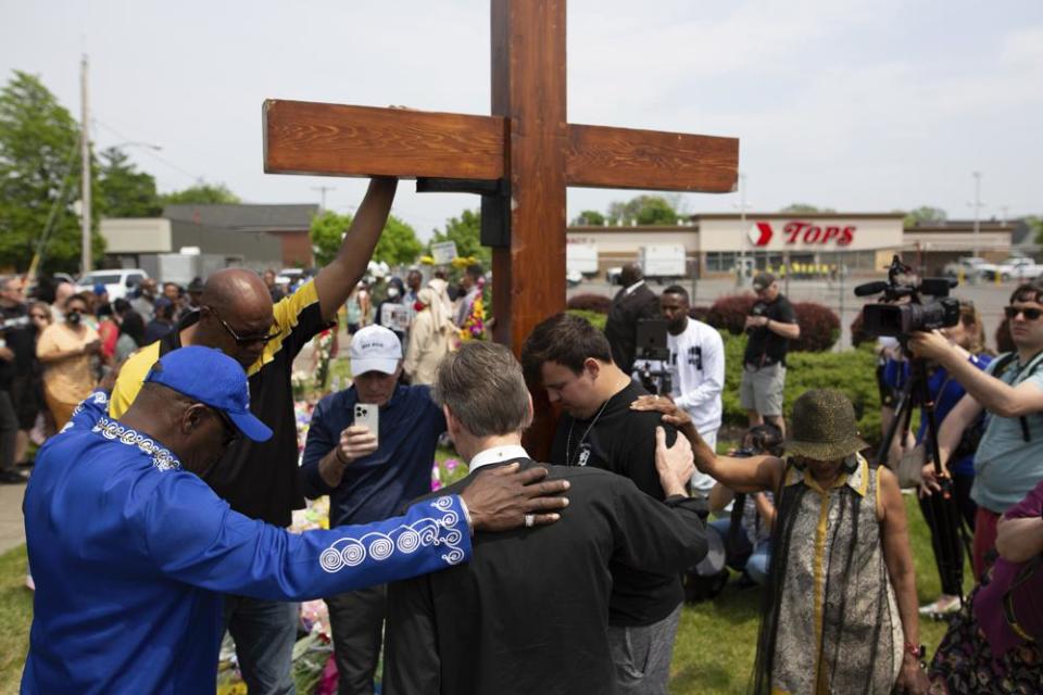 A group prays at the site of a memorial for the victims of the Buffalo supermarket shooting outside the Tops Friendly Market on Saturday, May 21, 2022, in Buffalo, N.Y. (AP Photo/Joshua Bessex)