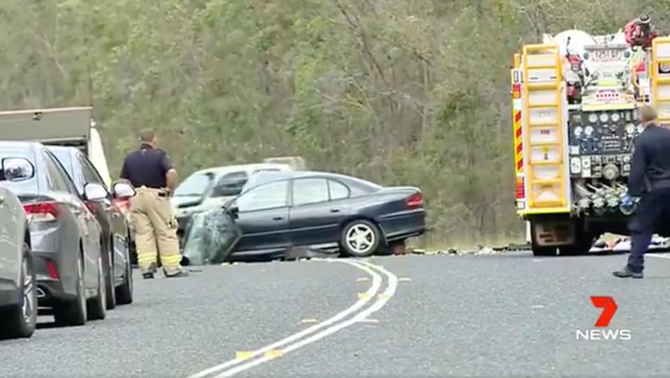 A fire fighters looks at a black Holden Commodore smashed on Childers Road.