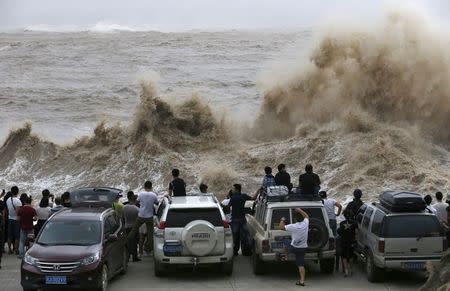 People look on as waves, under the influence of Typhoon Chan-hom, hit the shore in Wenling, Zhejiang province, China, July 10, 2015. REUTERS/William Hong