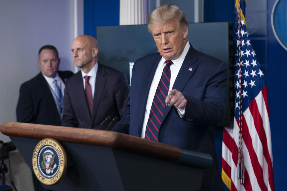 President Donald Trump speaks, accompanied by Food and Drug Administration Commissioner Dr. Stephen Hahn, center, during a media briefing in the James Brady Briefing Room of the White House, Sunday, Aug. 23, 2020, in Washington.(AP Photo/Alex Brandon)