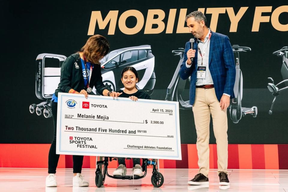 Melanie Mejia of Lodi received a Challenged Athletes Foundation grant from CEO Kristine Entwistle Challenged Athletes Foundation and Toyota Northeast Region Vehicle Operations Manager Darius Eftekhar at the 2023 New York International Auto Show in April.