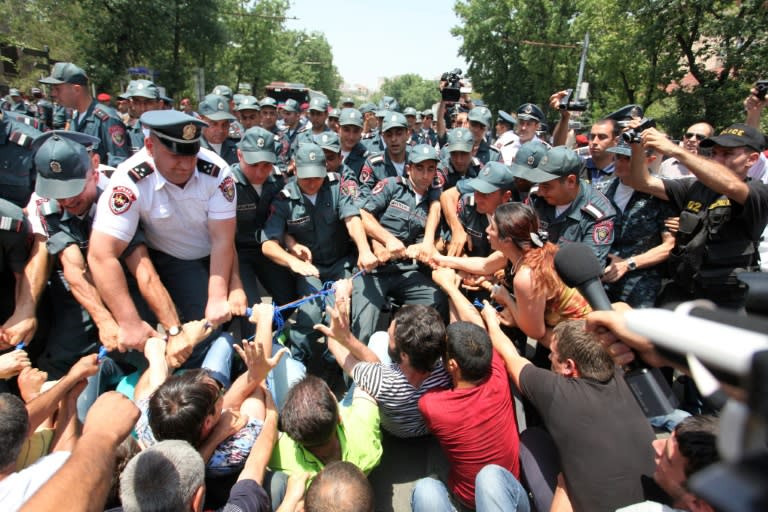 Police officers try to disperse demonstrators protesting against electricity price hikes in central Yerevan on July 6, 2015