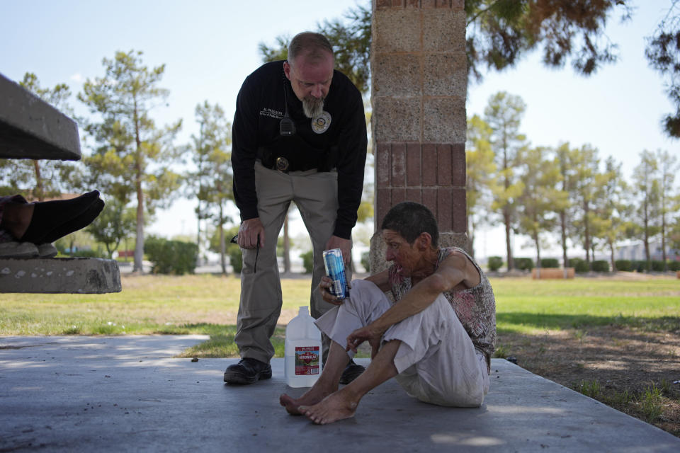 Mark Paulson, a Public Response and Code Enforcement officer, checks on Deb Billet, 66, before calling an ambulance to take her to a hospital for heat-related symptoms Wednesday, July 10, 2024, in Henderson, Nev. Billet has been living on the street. About 14 officers from the Office of Public Response drove around the city Wednesday offering water, electrolytes, free bus tickets and rides to cooling centers during a heat emergency. (AP Photo/John Locher)
