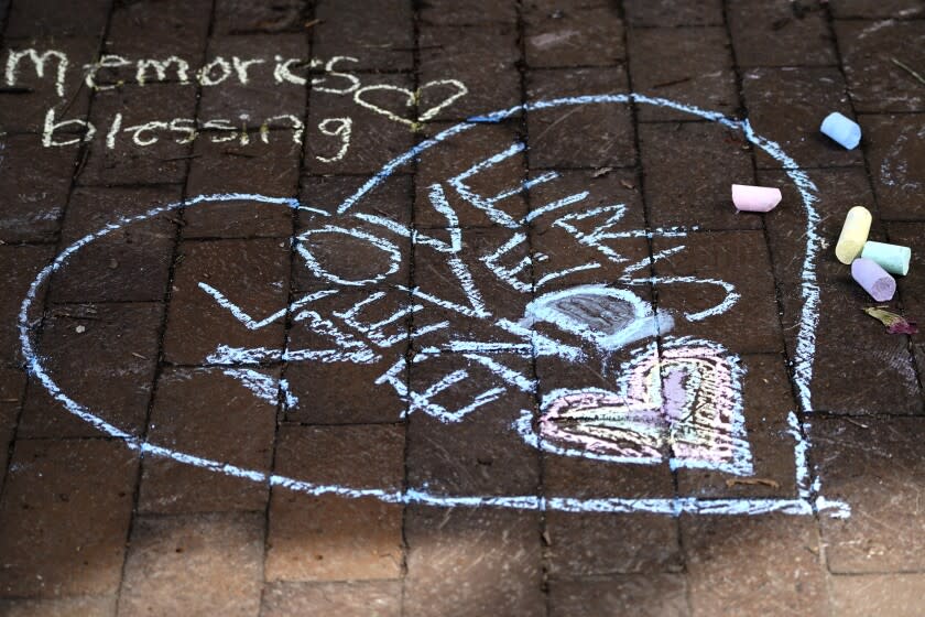 Chalk written signs dedicated to the seven people killed in Monday's Fourth of July mass shooting are pictured on a sidewalk at a memorial site, Thursday, July 7, 2022, in Highland Park, Ill. (AP Photo/Nam Y. Huh)