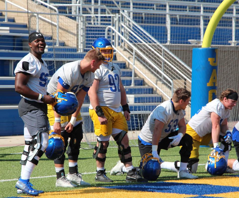 Defensive end Randy Keumogne (far left) teases a teammate during practice Friday at Dana J. Dykhouse Stadium.