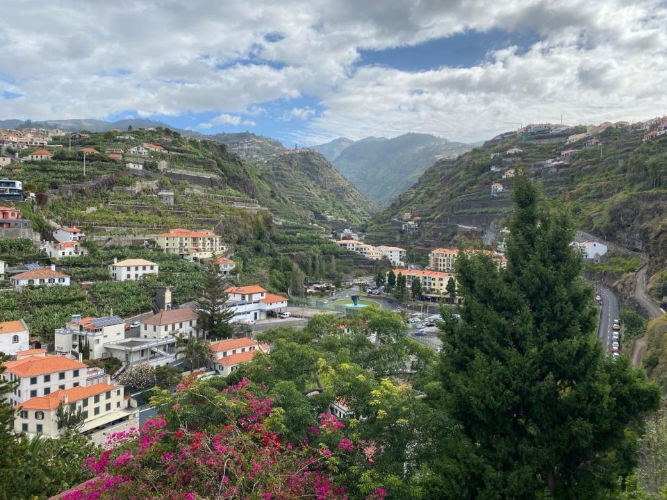 A view of buildings scattered among mountains in a semi-tropical landscape.