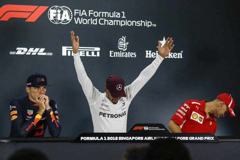 Mercedes driver Lewis Hamilton, center, of Britain reacts during a press conference following his Singapore Formula One Grand Prix win at the Marina Bay City Circuit in Singapore, Sunday, Sept. 16, 2018. Max Verstappen of Netherlands, left, and Sebastian Vettel of Germany, right. (AP Photo/Yong Teck Lim)