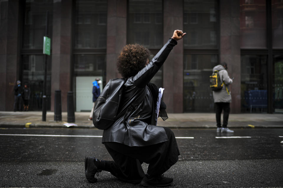 A woman kneels during a Black Lives Matter rally in London, Saturday, June 6, 2020, as people protest against the killing of George Floyd by police officers in Minneapolis, USA. Floyd, a black man, died after he was restrained by Minneapolis police while in custody on May 25 in Minnesota. (AP Photo/Alberto Pezzali)