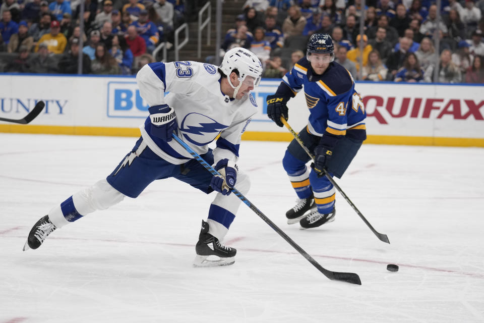 Tampa Bay Lightning's Michael Eyssimont (23) and St. Louis Blues' Scott Perunovich (48) chase after a loose puck during the first period of an NHL hockey game Tuesday, Nov. 14, 2023, in St. Louis. (AP Photo/Jeff Roberson)