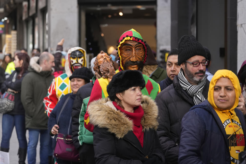 Two people in masks join a Christmas lottery tickets queue in downtown Madrid, Spain, Wednesday, Dec. 21, 2022. Spain's bumper Christmas lottery draw known as El Gordo, or The Fat One will be held on Dec. 22. (AP Photo/Paul White)