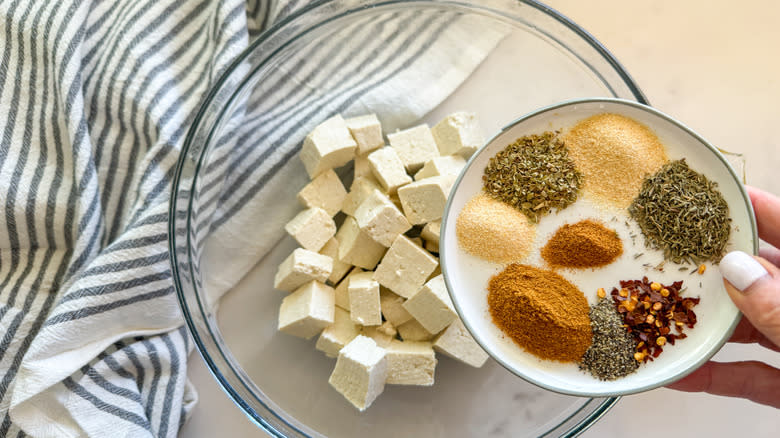 hand adding spices to bowl