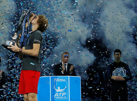 Tennis - ATP Finals - The O2, London, Britain - November 18, 2018 Germany's Alexander Zverev celebrates by kissing the trophy after winning the final as second placed Serbia's Novak Djokovic (R) looks on holding his trophy Action Images via Reuters/Andrew Couldridge