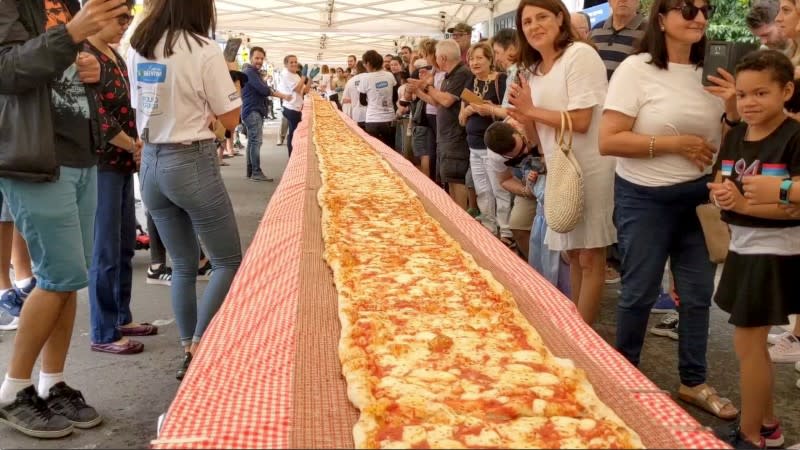People look on as a 100m long margherita pizza sits on a table before receiving its final toppings as part of a charity event to raise funds for the New South Wales Rural Fire Service, in Sydney