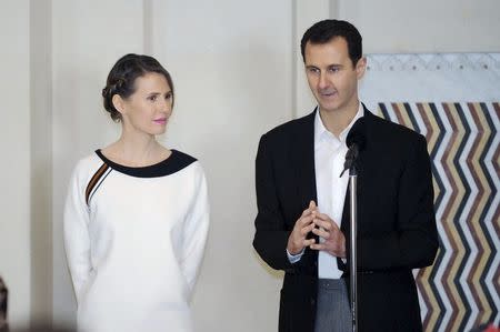 Syria's President Bashar al-Assad stands next to his wife Asma, as he addresses injured soldiers and their mothers during a celebration marking Syrian Mother's Day in Damascus, in this handout picture provided by SANA on March 21, 2016. REUTERS/SANA/Handout via Reuters