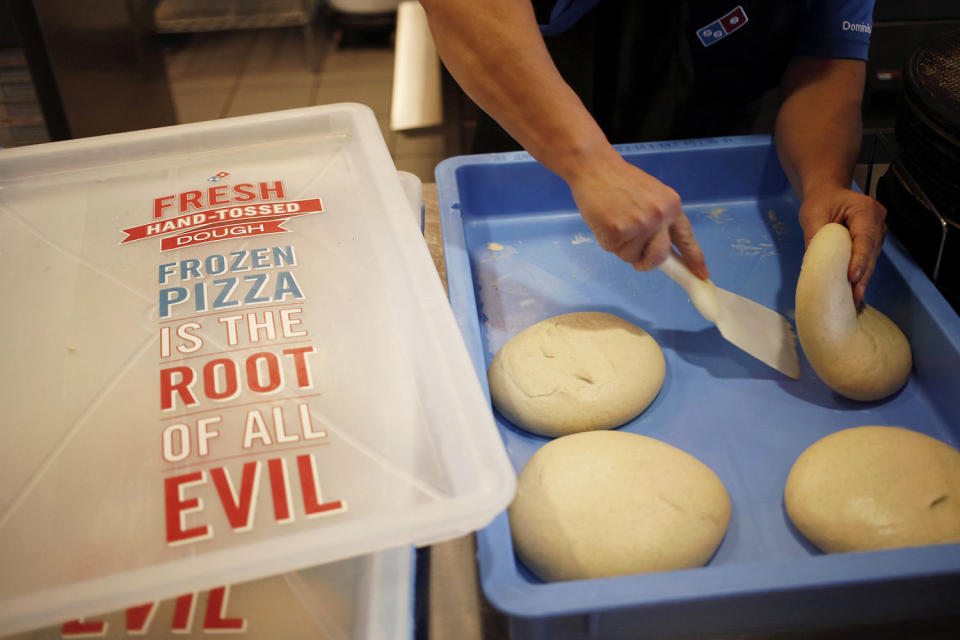 Store supervisor Kim Hopkins grabs a dough ball to make pizza during lunch hour at a Domino's Pizza Inc. (Luke Sharrett / Getty Images)
