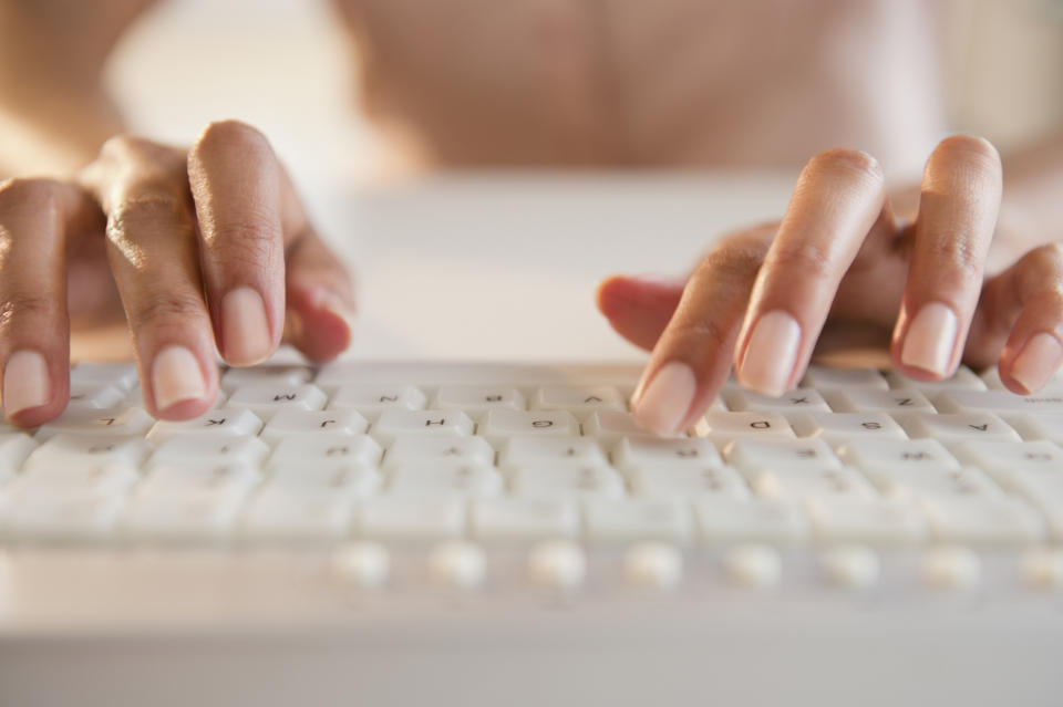 Person's hands typing on a keyboard, close-up view, focusing on the activity of typing