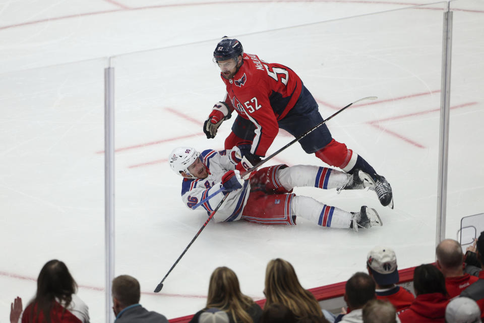 Washington Capitals defenseman Dylan McIlrath (52) checks New York Rangers center Jack Roslovic (96) during the third period in Game 3 of an NHL hockey Stanley Cup first-round playoff series, Friday, April 26, 2024, in Washington. (AP Photo/Tom Brenner)