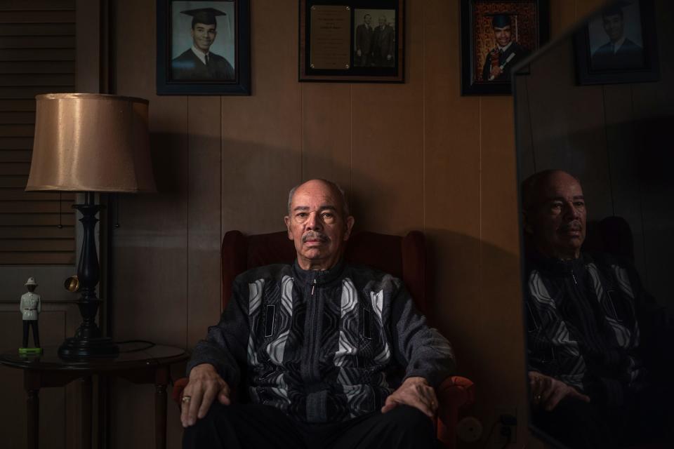 Judge Ulysses Boykin sits underneath photos of himself, left, from 1963 and his son Peter Boykin's, right, 1994 graduating photos from Cass Tech in a room at his home in Detroit on Friday, Feb. 16, 2024.