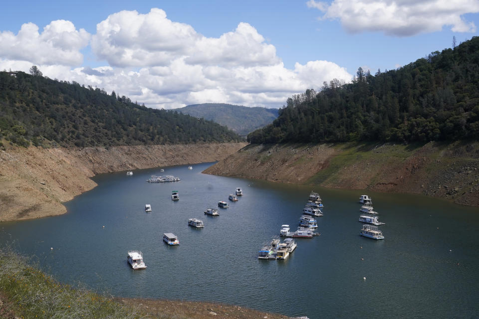 FILE - Houseboats sit in the drought-lowered waters of Oroville Lake, near Oroville, Calif., Tuesday, April 19, 2022. The State Water Resources Control board voted Tuesday, May 24, 2022, to ban watering turf and to require local water districts to adopt more aggressive conservation measures. The board's vote came a day after Gov. Gavin Newsom urged local water districts to do more to save water. (AP Photo/Rich Pedroncelli, File)