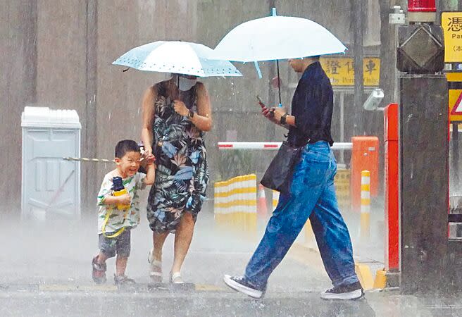 北市昨日午後下起一場大雷雨，大人撐著傘牽著小朋友在雨中快步前行，小朋友臉上則露出笑容。（姚志平攝）