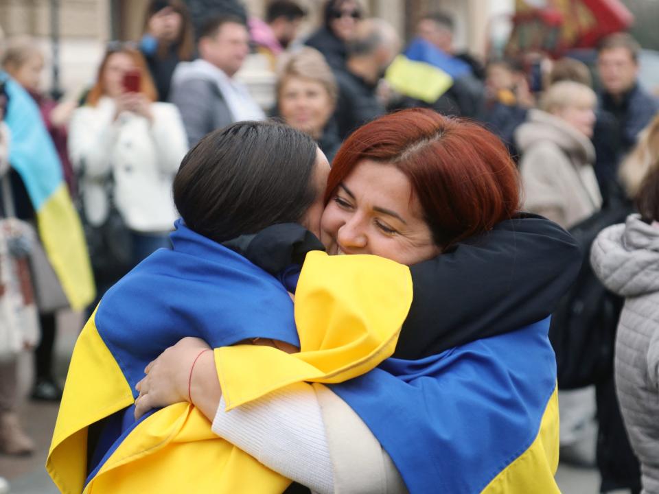 Residents of Kherson temporarily living in Odessa, wearing Ukrainian flags, celebrate the liberation of their native town in front of The Odessa National Academic Opera and Ballet Theatre in Odessa, on November 12, 2022, amid Russia's invasion of Ukraine.