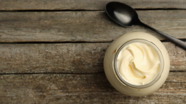 Spoonful of mayonnaise in front of jar