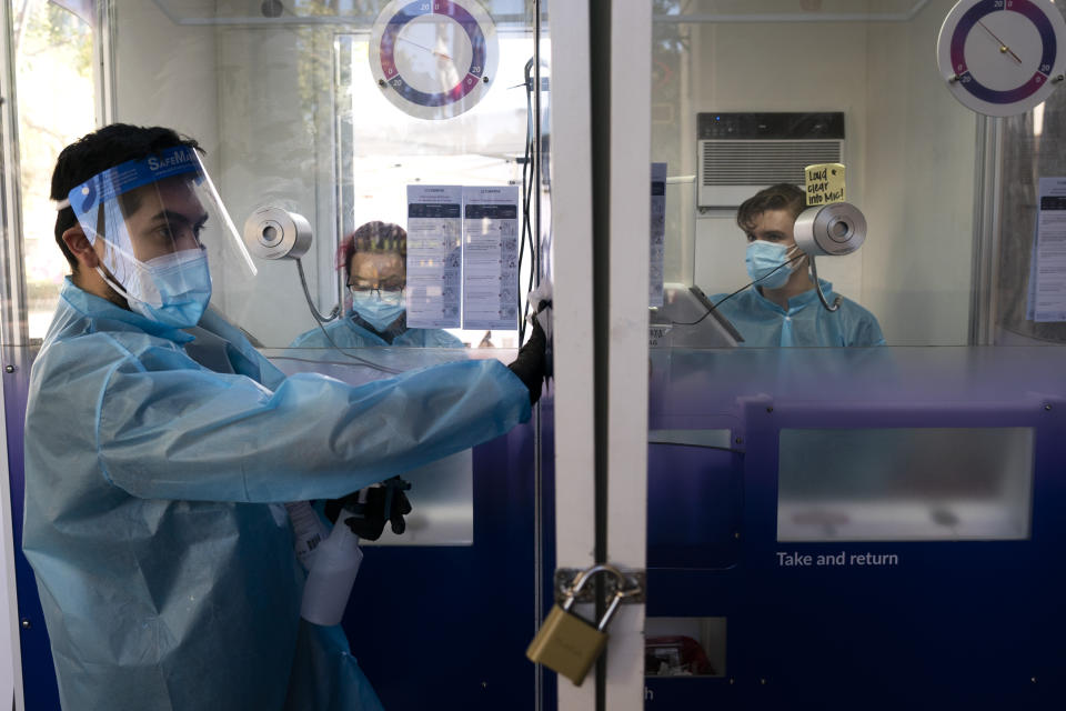 FILE - In this Dec. 9, 2020, file photo, test specialist Elijah Sanchez disinfects a testing booth at a COVID-19 testing site in Los Angeles. As officials met to discuss approval of a COVID-19 vaccine on Thursday, Dec. 10, the number of coronavirus deaths has grown bleaker than ever. (AP Photo/Jae C. Hong, File)