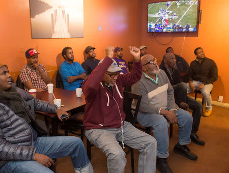 Jamal Said (C) of St. Louis Park raises his arms as he cheers for the Minnesota Vikings in the NFC Championship game at the Capitol Cafe, a popular Somali coffee shop, ahead of the NFL's Super Bowl in Minneapolis, Minnesota, U.S. January 20, 2018. REUTERS/Craig Lassig/Files