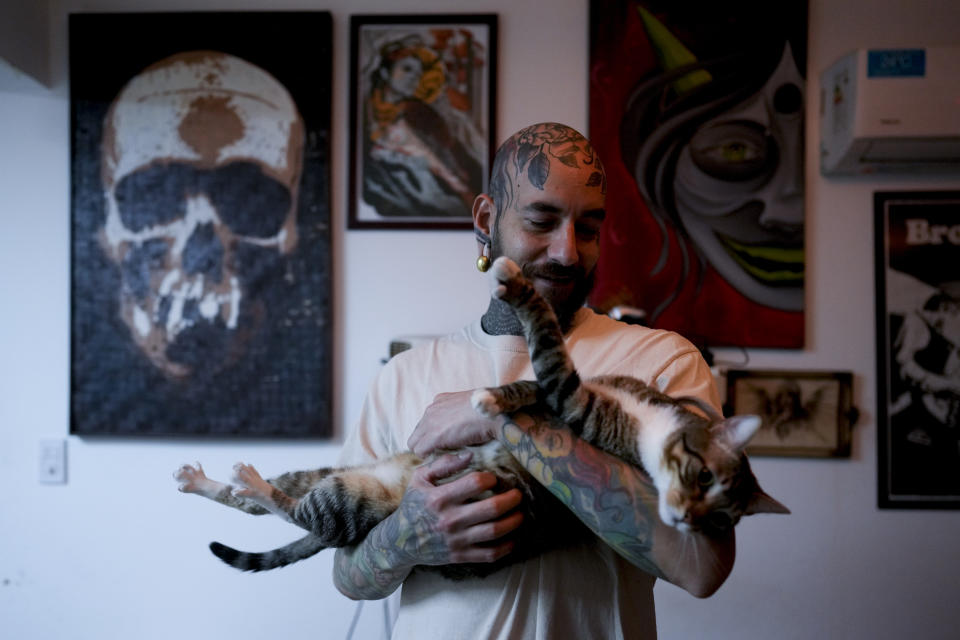 Tulio holds his cat at home in Buenos Aires, Argentina, Wednesday, Sept. 8, 2021. Tulio adopted two cats during the COVID-19 lockdown for their companionship during months at home. (AP Photo/Natacha Pisarenko)