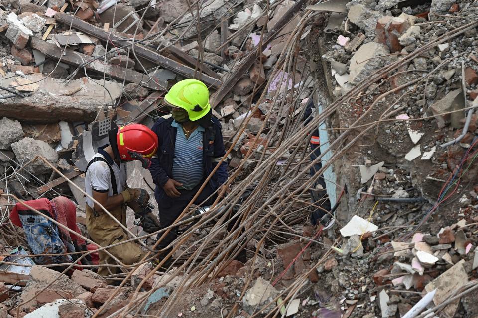 Rescue workers search for survivors in the rubble of a collapsed five-storey apartment building in Mahad. (Photo by PUNIT PARANJPE/AFP via Getty Images)