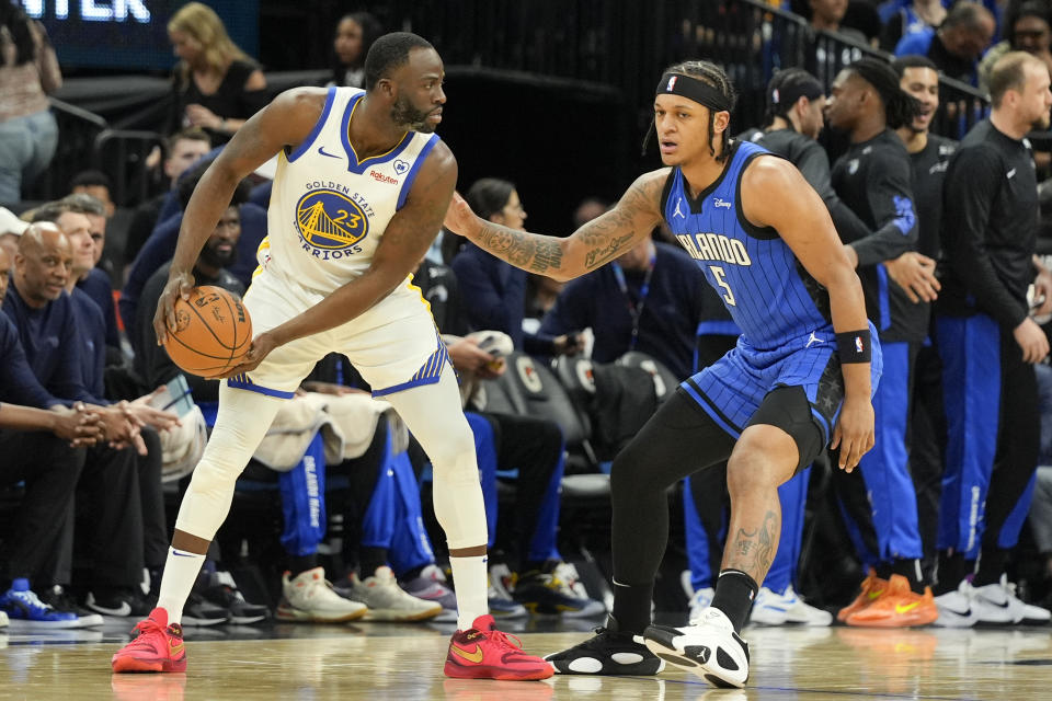 Golden State Warriors forward Draymond Green (23) looks for an opening as Orlando Magic forward Paolo Banchero (5) defends during the first half of an NBA basketball game Wednesday, March 27, 2024, in Orlando, Fla. (AP Photo/John Raoux)