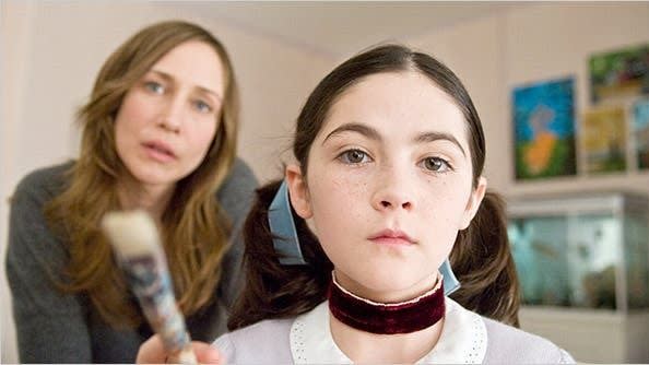 a kid with a velvet ribbon around her neck looks in the mirror while her mother stands behind her in a scene from orphan, a good housekeeping pick for best halloween movies