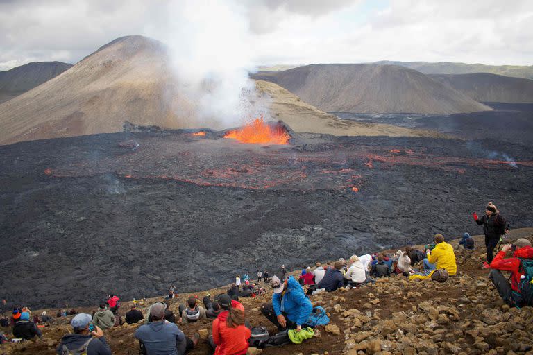 Onlookers watch as lava flows from the vulcano in Fagradalsfjall, Iceland, around 40 kilometres (25 miles) from the capital Reykjavik, on August 10, 2022, following an eruption that has been ongoing since August 3, 2022. - The volcano erupted on August 3, some 40 kilometres (25 miles) from Reykjavik, near the site of the Mount Fagradalsfjall volcano that erupted for six months in March-September 2021, mesmerising tourists and spectators who flocked to the scene. (Photo by Jeremie RICHARD / AFP)