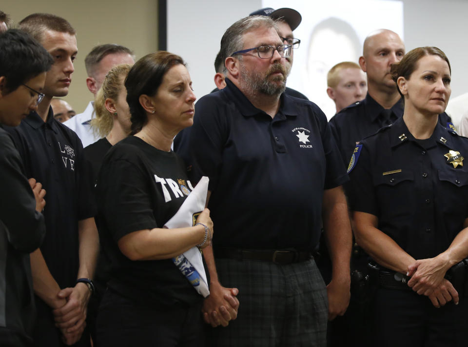 CORRECTS FIRST NAME TO KELLEY, NOT KELLY - With their eyes closed, Kelley and Denis O'Sullivan, the parents of slain Sacramento Police officer Tara O'Sullivan, hold hands during a news conference in Sacramento, Calif., Tuesday, June 25, 2019. Denis O'Sullivan told the media that any notion that the Sacramento Police Department was responsible for her death was extremely offensive and hurtful. It took rescuers 45 minutes to reach Tara O'Sullivan after she was shot by gunman, who kept shooting at police, during a domestic violence call last week. (AP Photo/Rich Pedroncelli)