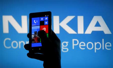 A woman poses with a Nokia Lumia smartphone in this photo illustration in the central Bosnian town of Zenica in this May 6, 2013 file photo. REUTERS/Dado Ruvic/Files